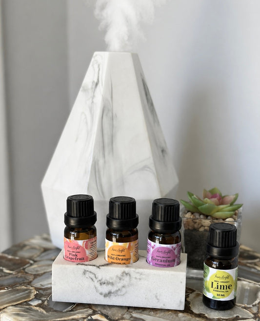 Set of essential oil bottles on a marble stand with a diffuser in the background.